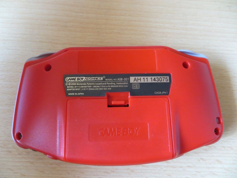 Unterseite des roten Game Boy Advance mit Batteriefach und Typenschild, Modell AGB-001